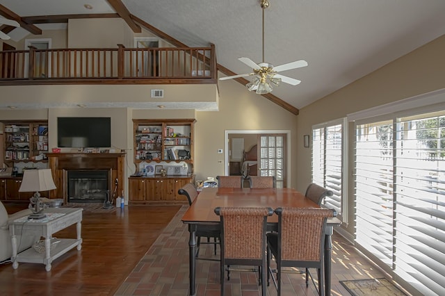 dining room featuring ceiling fan, beamed ceiling, high vaulted ceiling, dark hardwood / wood-style floors, and a textured ceiling