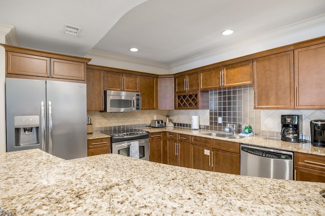 10 Harbor Blvd Unit W528, Destin, FL 32541 - kitchen featuring appliances with stainless steel finishes, brown cabinets, light stone counters, crown molding, and decorative backsplash