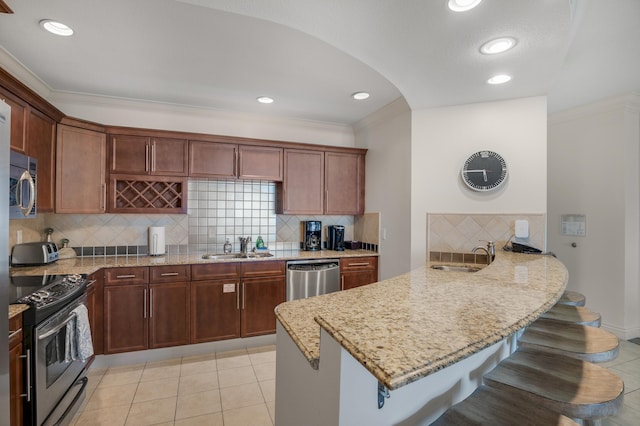 10 Harbor Blvd Unit W528, Destin, FL 32541 - kitchen featuring appliances with stainless steel finishes, a peninsula, a breakfast bar, backsplash, and light stone countertops