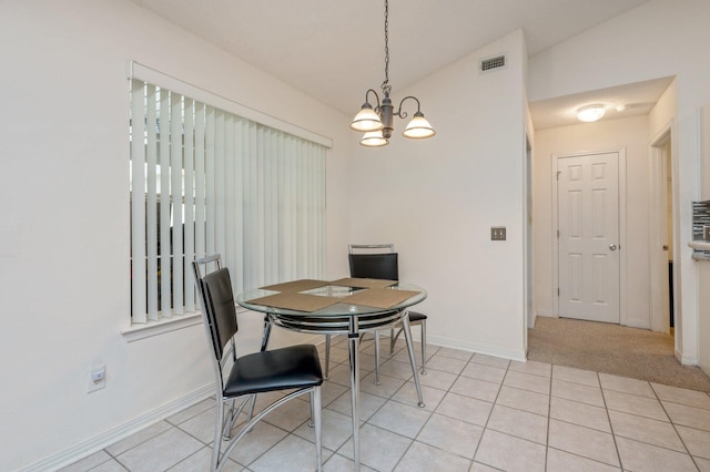 dining room with a notable chandelier, light tile patterned floors, and vaulted ceiling