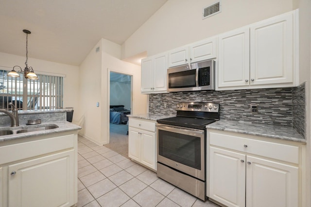 kitchen featuring sink, vaulted ceiling, a notable chandelier, white cabinetry, and stainless steel appliances