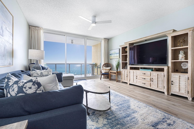 living area with a ceiling fan, a textured ceiling, wood finished floors, and expansive windows