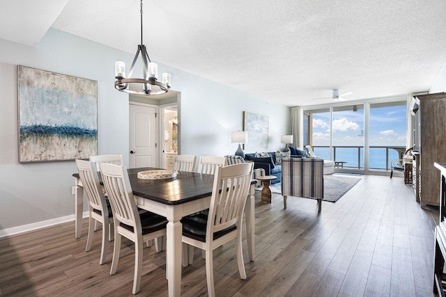 dining area with ceiling fan with notable chandelier, expansive windows, a textured ceiling, wood finished floors, and baseboards