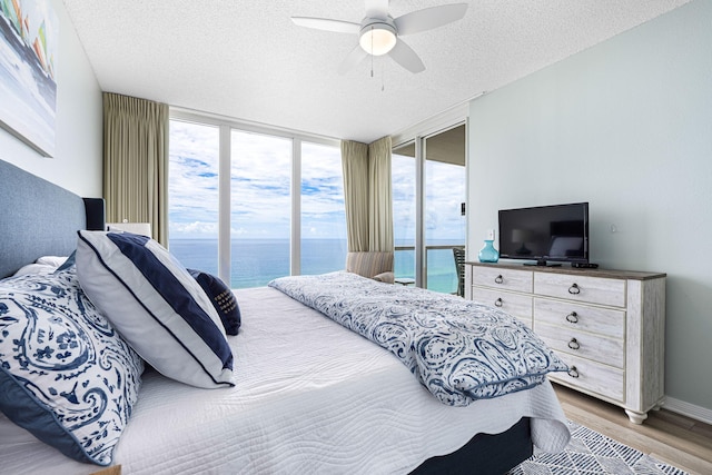 bedroom with access to exterior, baseboards, ceiling fan, wood finished floors, and a textured ceiling