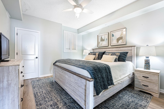 bedroom with light wood-type flooring, baseboards, a textured ceiling, and a ceiling fan