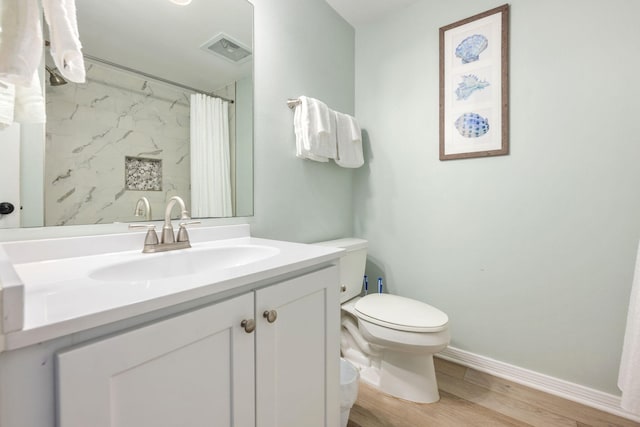 bathroom featuring visible vents, toilet, wood finished floors, baseboards, and vanity