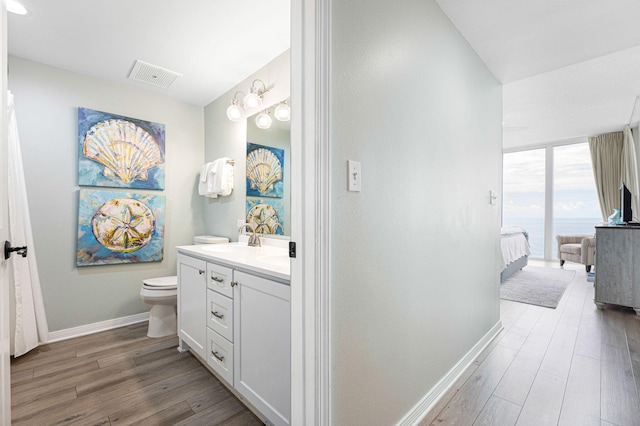 bathroom with visible vents, connected bathroom, baseboards, wood finished floors, and vanity