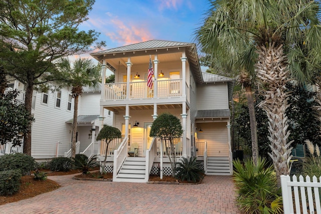 coastal inspired home featuring a balcony and covered porch