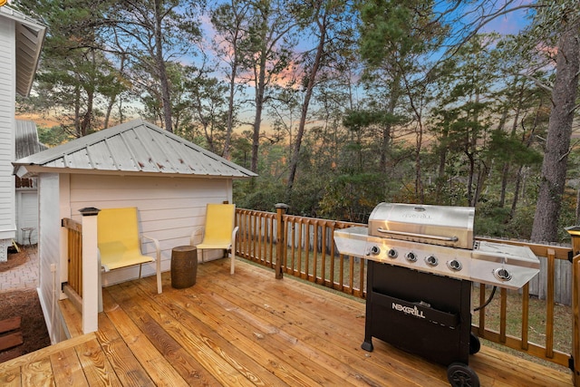 deck at dusk featuring a grill