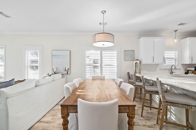 dining room with ornamental molding, light hardwood / wood-style flooring, and a healthy amount of sunlight