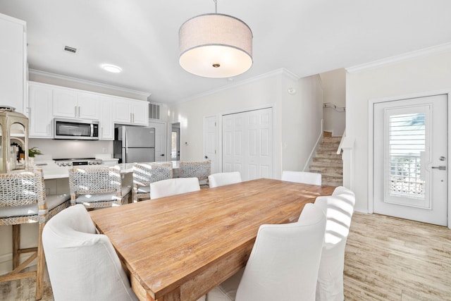 dining space featuring ornamental molding and light wood-type flooring