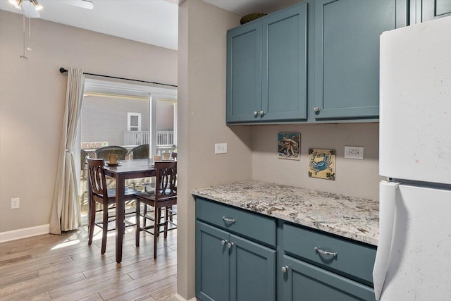 kitchen with ceiling fan, white refrigerator, blue cabinetry, and light hardwood / wood-style flooring