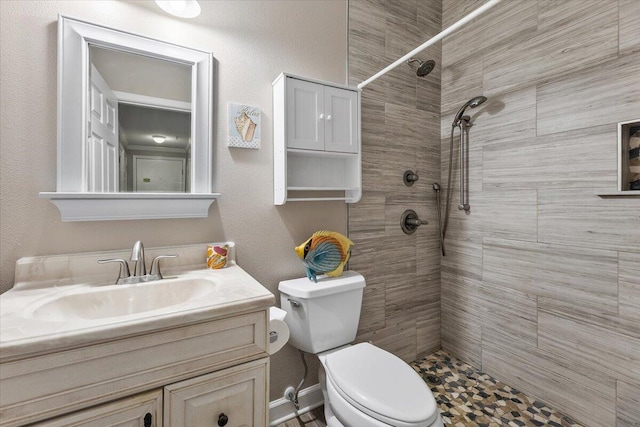 bathroom with tiled shower, vanity, and toilet