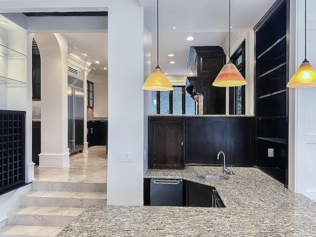 kitchen featuring decorative light fixtures, stainless steel built in refrigerator, sink, dark stone countertops, and crown molding