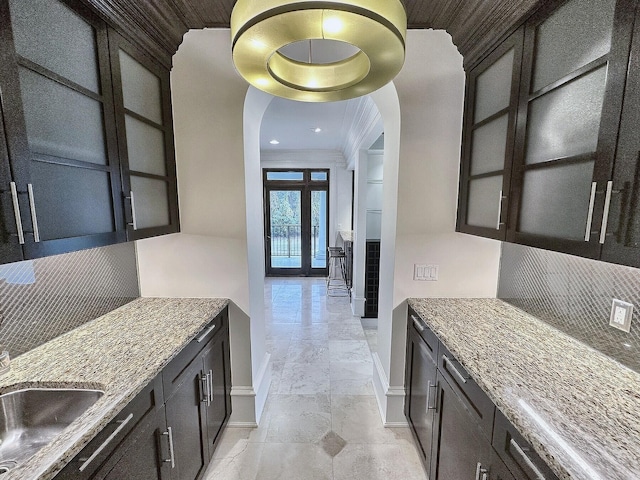 kitchen with ornamental molding, dark stone counters, sink, and backsplash