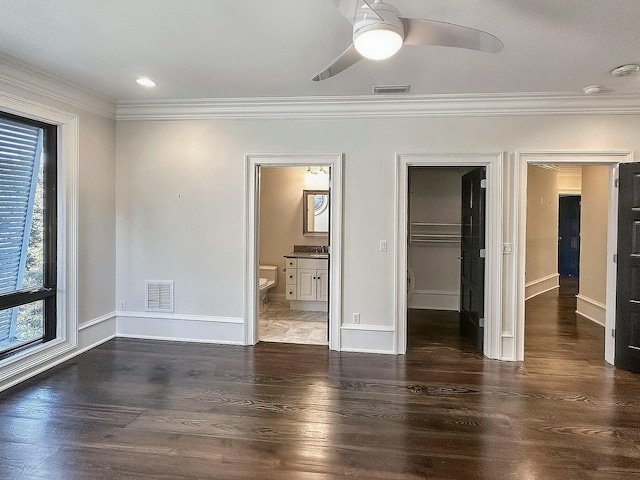 unfurnished bedroom featuring ensuite bathroom, a spacious closet, ornamental molding, dark hardwood / wood-style floors, and a closet