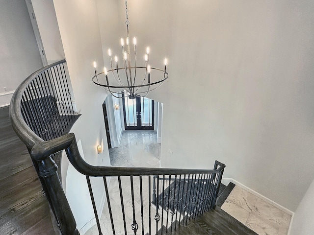 stairs featuring an inviting chandelier, a towering ceiling, and french doors