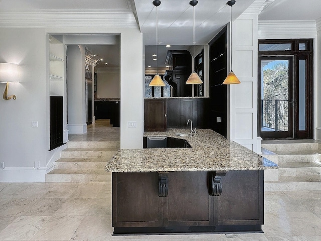 kitchen with sink, hanging light fixtures, dark brown cabinetry, light stone counters, and crown molding