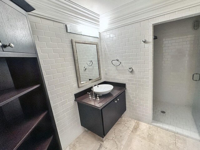 bathroom featuring ornamental molding, tiled shower, tile walls, and vanity