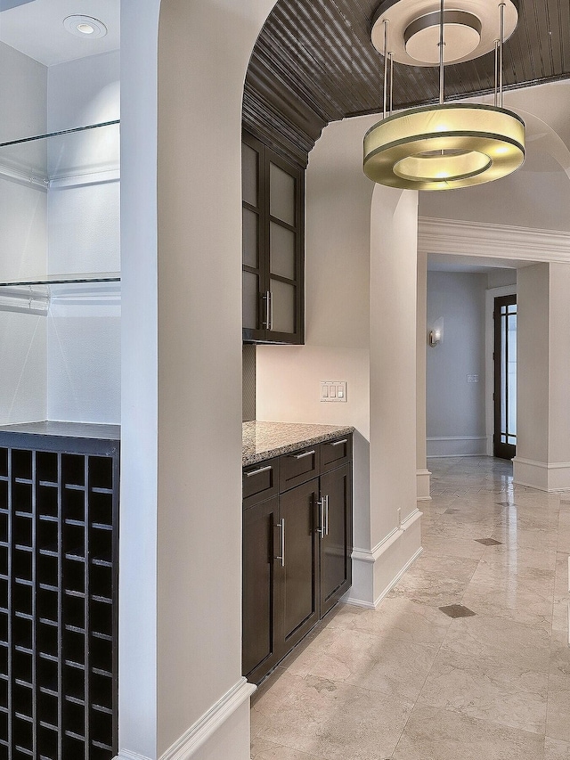 bar featuring dark brown cabinetry and light stone counters