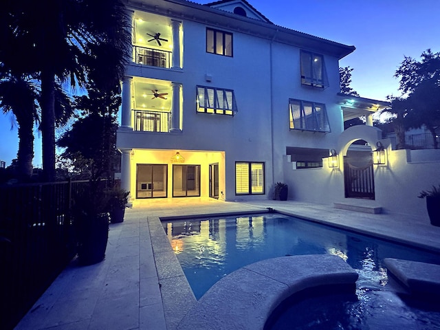 pool at dusk with a patio and ceiling fan