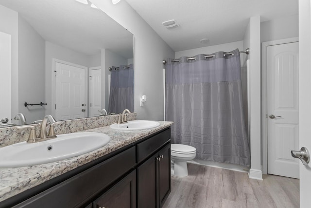 full bathroom with hardwood / wood-style flooring, toilet, vanity, and shower / bathtub combination with curtain