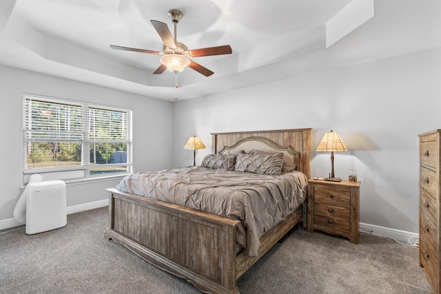 carpeted bedroom with a raised ceiling and ceiling fan