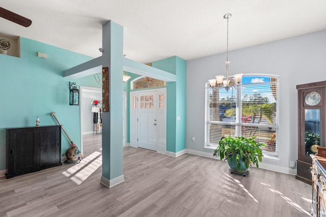 interior space with light wood-type flooring, vaulted ceiling, and a chandelier