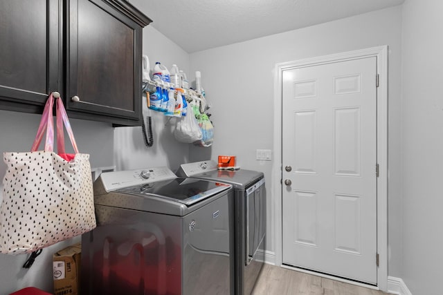 laundry room featuring light hardwood / wood-style floors, washing machine and clothes dryer, and cabinets