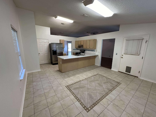 kitchen featuring kitchen peninsula, stainless steel fridge with ice dispenser, light tile patterned flooring, and a textured ceiling