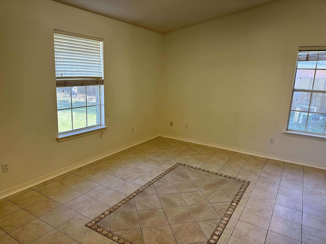 tiled empty room featuring a textured ceiling