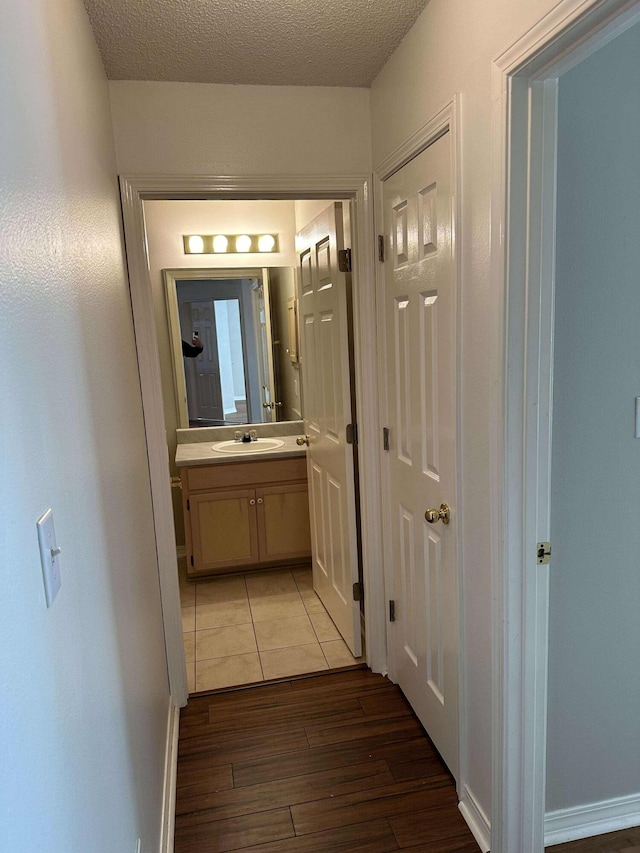 corridor featuring dark hardwood / wood-style flooring, a textured ceiling, and sink