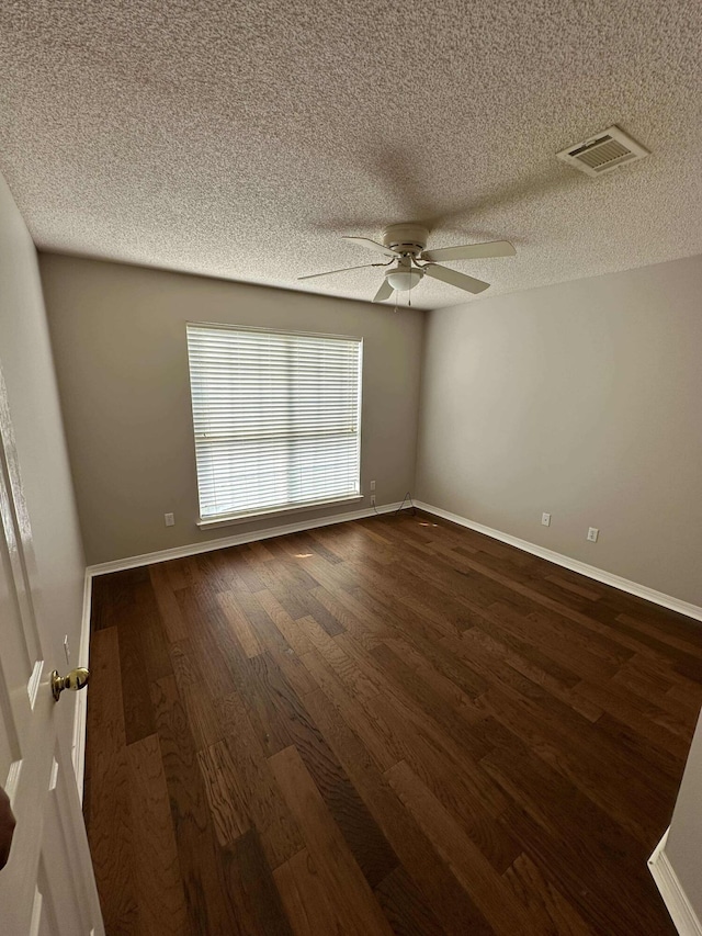 empty room with ceiling fan, dark wood-type flooring, and a textured ceiling