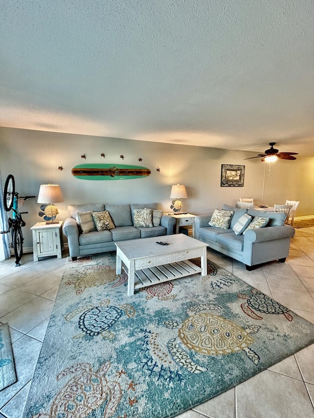 living room with ceiling fan, light tile patterned flooring, and a textured ceiling