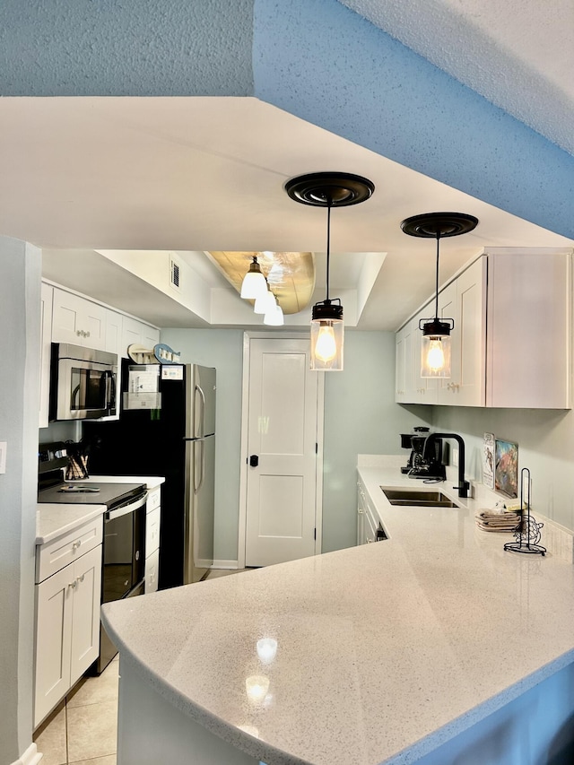 kitchen with a tray ceiling, kitchen peninsula, white cabinets, and stainless steel appliances