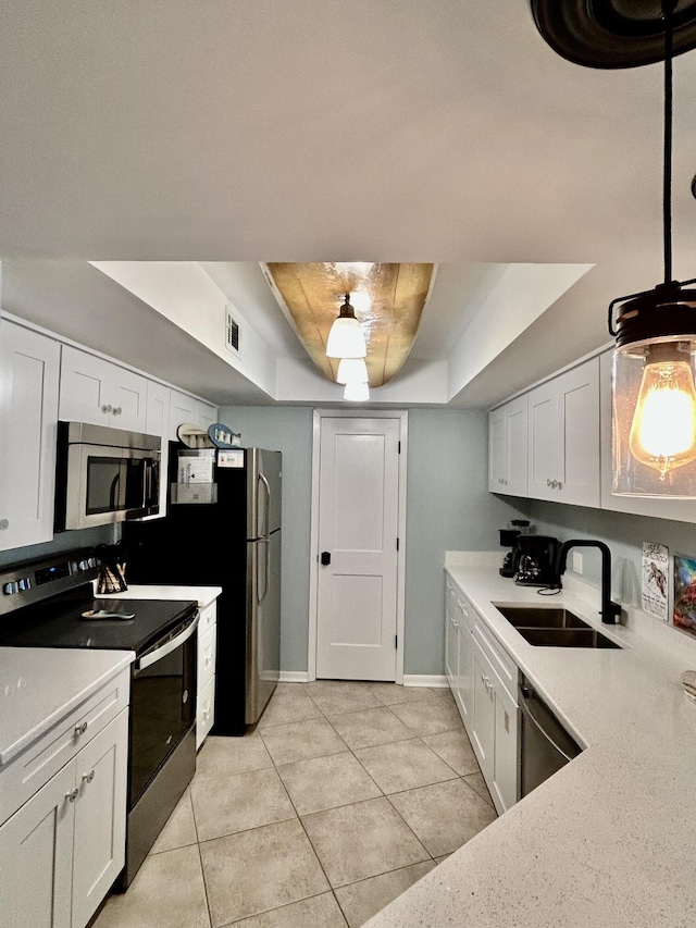 kitchen featuring appliances with stainless steel finishes, a tray ceiling, white cabinetry, and sink