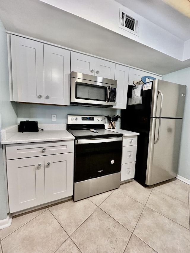 kitchen with white cabinets, appliances with stainless steel finishes, and light tile patterned floors