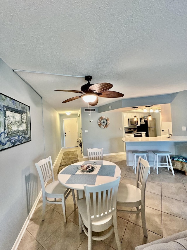 tiled dining room featuring ceiling fan, sink, and a textured ceiling