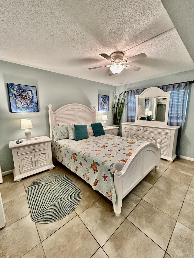 tiled bedroom with ceiling fan and a textured ceiling