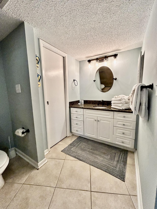 bathroom with tile patterned flooring, vanity, a textured ceiling, and toilet