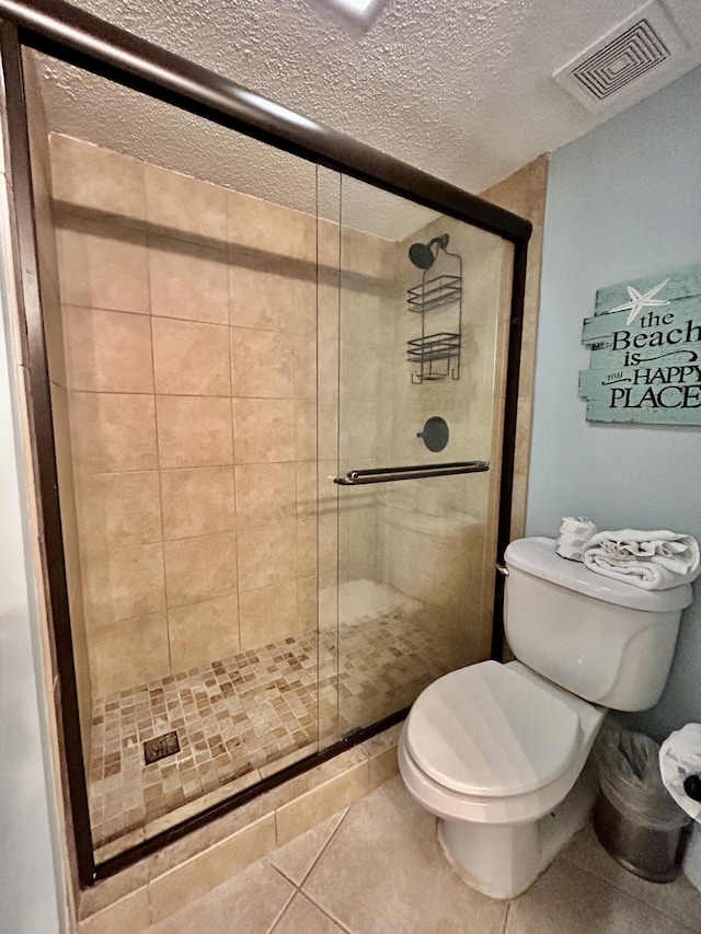 bathroom with tile patterned flooring, a shower with shower door, a textured ceiling, and toilet