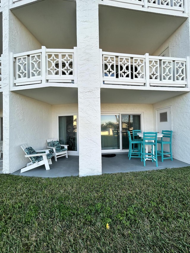 back of property with a patio area, a balcony, and a yard