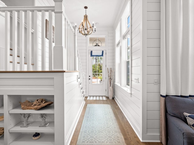 doorway featuring hardwood / wood-style flooring, an inviting chandelier, and crown molding