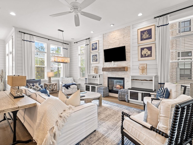 living room with hardwood / wood-style floors, ceiling fan, crown molding, and a fireplace