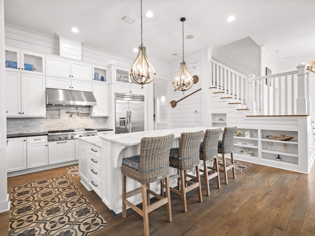 kitchen featuring a center island, dark wood-type flooring, dark stone counters, white cabinets, and stainless steel appliances