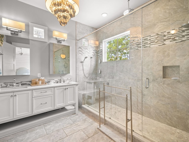 bathroom with vanity, a shower with shower door, and ceiling fan with notable chandelier