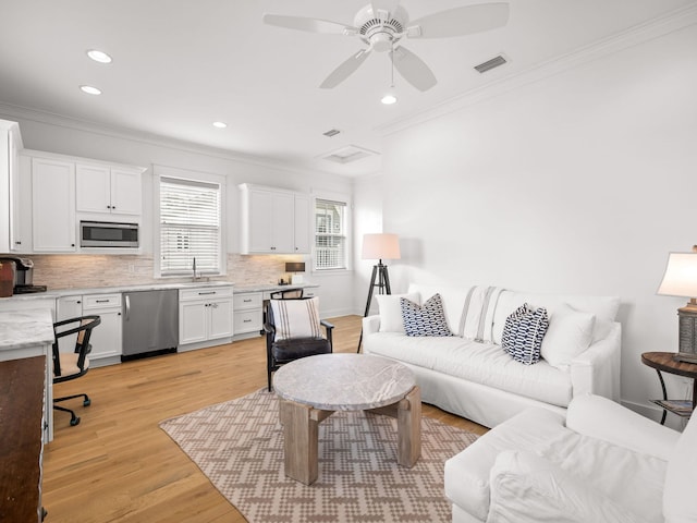 living room with ceiling fan, light hardwood / wood-style floors, ornamental molding, and sink