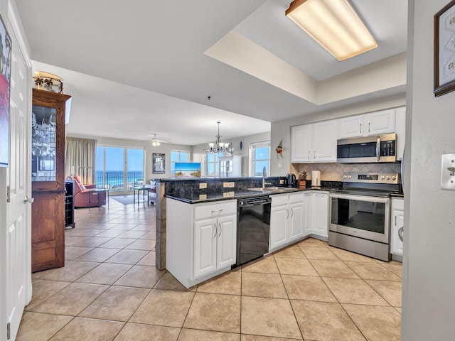 kitchen featuring white cabinets, ceiling fan with notable chandelier, appliances with stainless steel finishes, tasteful backsplash, and kitchen peninsula