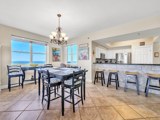 dining area with a water view, a chandelier, and light tile patterned floors