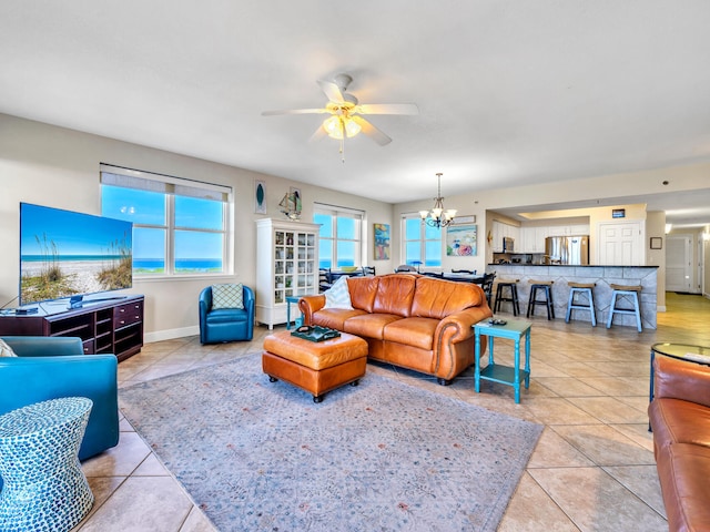 living room with light tile patterned floors and ceiling fan with notable chandelier